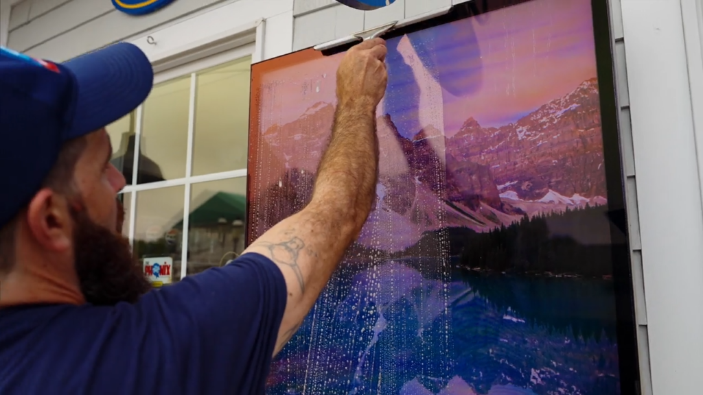 An A&A employee cleans a video screen outside of Del's Lemonade in Warwick, RI